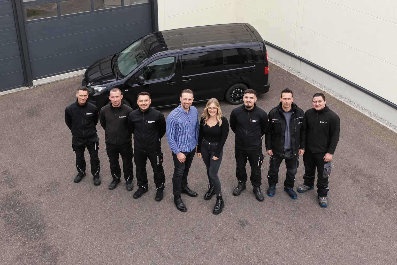 Das GDK-Team vor einem Fahrzeug am Betriebsgebäude